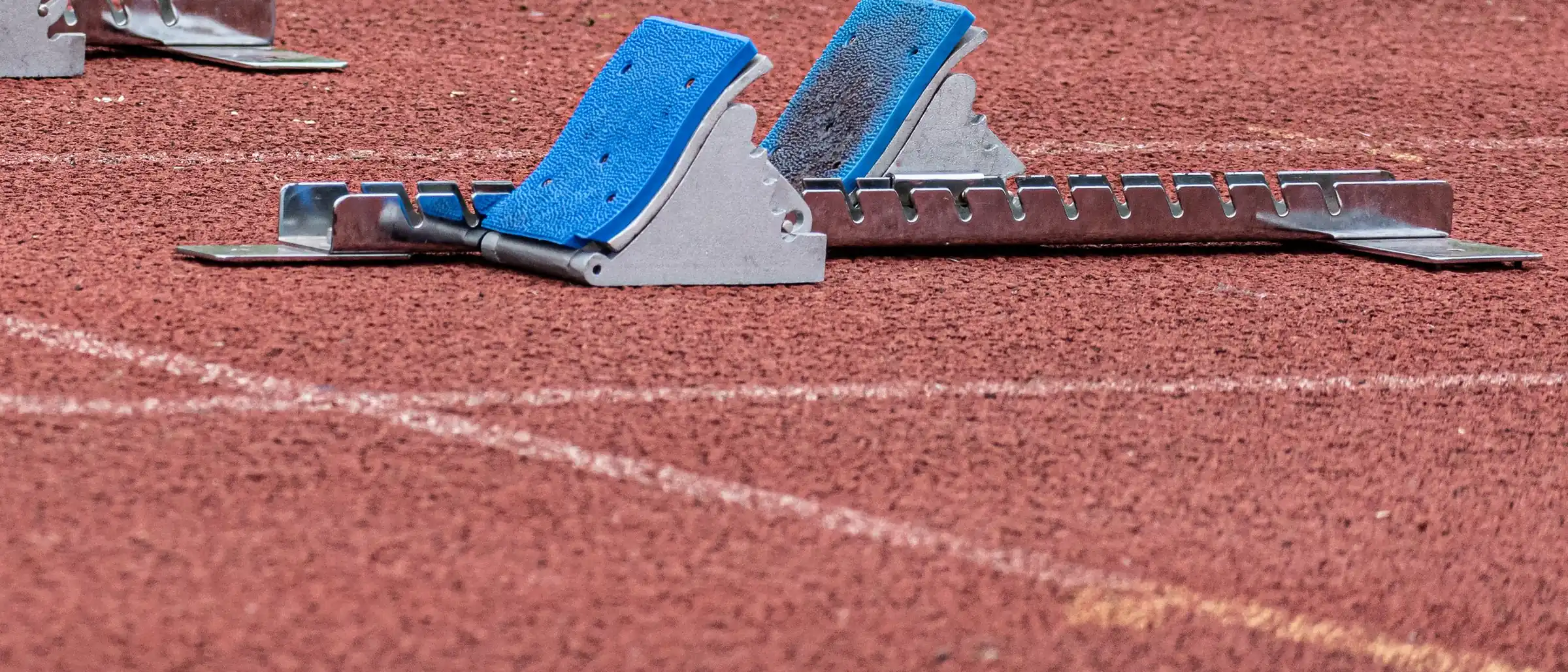 Starting blocks set on a red running track.